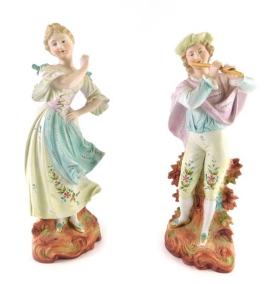 A pair of early 20thC Austrian bisque figures, of a lady and gentleman each dressed in finery, on scroll bases, 38cm high.