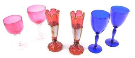 A pair of 19thC Bohemian ruby glass vases, each with milk glass panels and gilt highlights, a double air twist ruby and clear glass wine glass, 17cm high, etc. (a quantity)