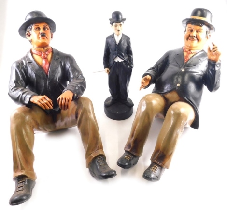 A resin Charlie Chaplin figure standing, 47cm high, and two others, Laurel & Hardy.