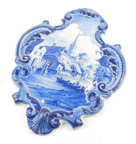 A 20thC Dutch Delft wall plaque, scroll outline, decorated with figures in boats before spire, 42cm high.