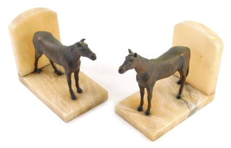 A pair golden onyx horse bookends, with shaped tops, 13cm high.