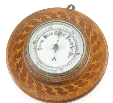 A 20thC oak cased aneroid wall barometer, with 12cm diameter dial, in elaborate inlaid scroll and floral case, with metal hanging top.