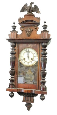 An early 20thC walnut cased small Vienna wall clock, with 12cm diameter dial flanked by quarter columns, with eagle finial, 57cm high.