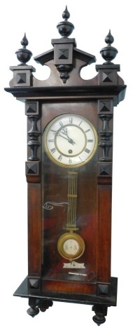 An early 20thC walnut cased Vienna wall clock, with broken arch pediment, cream coloured enamel dial with Roman numerals, etc., 87cm high.