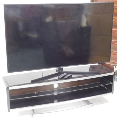 A Samsung 65" flat screen smart television, model UE65NU7400U, with two remote controls and wire, on a TV stand, 150cm wide, 41cm deep. Purchased 2019 original cost total: £1200.