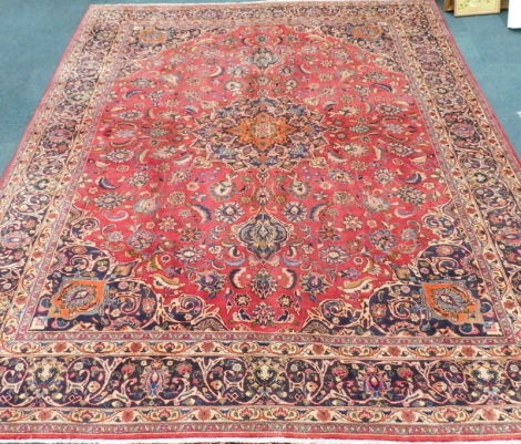 A large Persian Mashed carpet, with red ground and floral medallion, 384cm x 305cm.