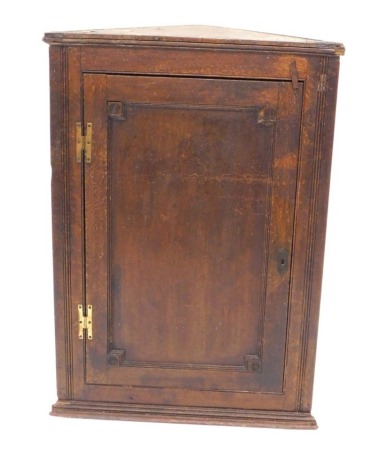 A 19thC oak hanging corner cabinet, with a single panel door and brass H hinges, 106cm high, 73cm wide.