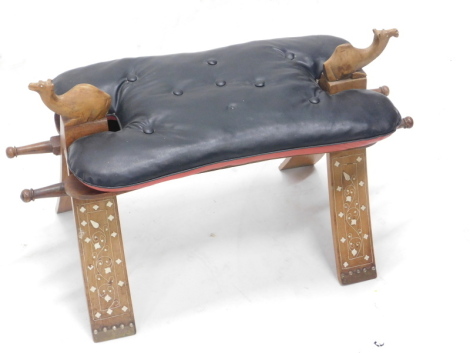 A mid to late 20thC hardwood and bone inlaid camel seat, carved with two camels and with a black leatherette cushion, 74cm wide. The upholstery in this lot does not comply with the 1988 (Fire & Fire Furnishing) Regulations, unless sold to a known exporter