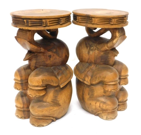 A pair of Eastern hardwood occasional tables, each carved in the form of an elephant, with a circular top, 50cm high, 27cm wide.