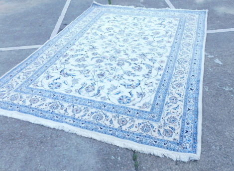 A Indian carpet with a design of flowers, scrolls, leaves, etc., on a cream ground within narrow blue borders, 247cm x 334cm.