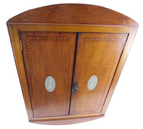 A late 19thC/early 20thC mahogany hanging corner cabinet, with a shaped crest, the feather banded doors each painted with Neo-Classical figures in pale blue Wedgwood style, 91cm high, 60cm wide.