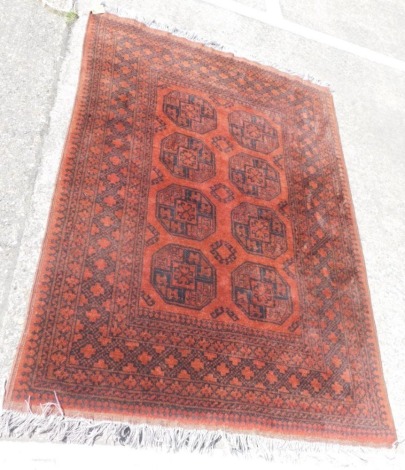 An Afghan rug, with a design of medallions, on orange ground with multiple borders, 174cm x 126cm.