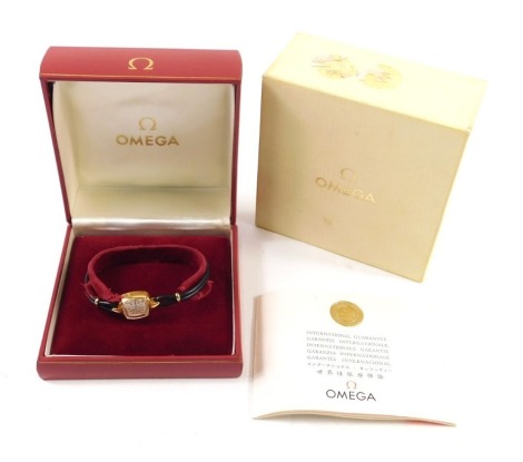 A Omega cocktail watch, with shaped square face, with 0.8cm dial, baton pointers, mother of pearl coloured face, black leather bracelet with gilt coloured mounts, in fitted case with outer box, paperwork and original receipt dated 1967 for £265.