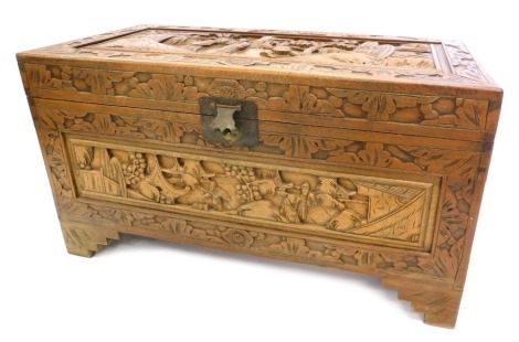 An Eastern camphorwood chest, carved overall with leaves, figures, buildings, etc., on bracket feet, 89cm wide.