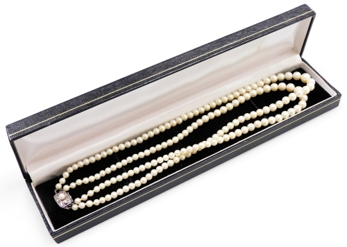 A double strand of Mikimoto graduated cultured pearls, with silver clasp decorated with a raised leaf pattern and additional central pearl, the reserve stamped M, 44cm long overall, largest central pearl 5mm.