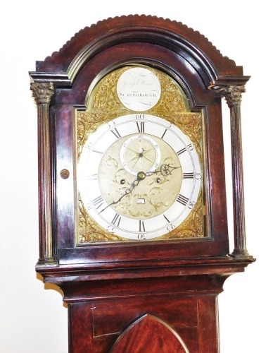 A George III mahogany longcase clock by Joseph Wood of Scarborough, the arched dial with foliate spandrels, silver chapter ring bearing Roman and Arabic numerals, subsidiary seconds dial and date aperture, eight day four pillar movement with bell strike,