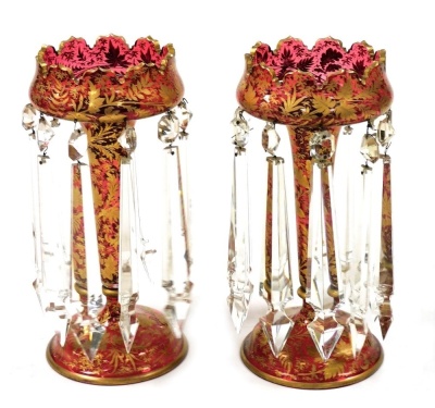 A pair of Victorian cranberry glass lustres, each with gilt embellishment and clear glass drops, 28cm high.