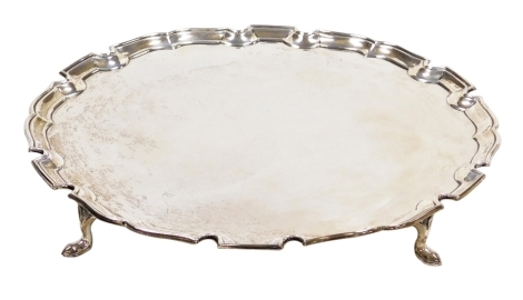 An Edward VIII silver salver, of plain form with piecrust border, raised on four hoof feet, Edward Barnard and Sons Ltd, London 1936, 21.25oz, 25cm diameter.