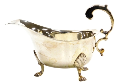 A George V silver sauce boat, with shaped rim and handle, raised on three lion paw feet, Birmingham 1932, 6.10oz, 17.5cm wide.