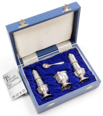 An Elizabeth II silver three piece cruet, comprising salt and pepper pot, and lidded mustard pot with blue glass liner and spoon, weighable silver 3.20oz, in fitted box.