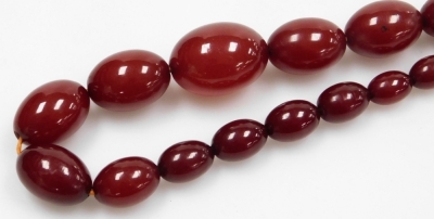 A string of graduated cherry amber beads, on a screw fitting, 71.2g. - 2