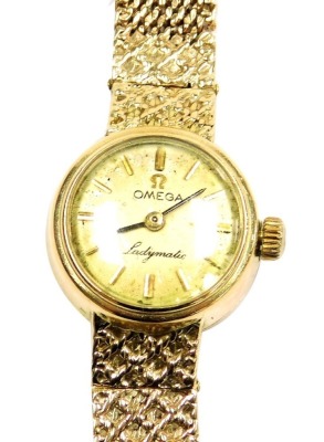 An Omega ladies 9ct gold Ladymatic wristwatch, the circular champagne dial bearing gold batons, on a mesh strap, 20.3g all in.