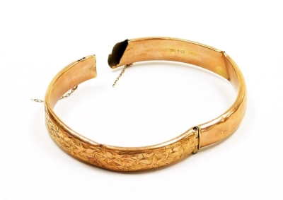 A 9ct rose gold bangle, with engraved foliate decoration, 8.5g. (AF)