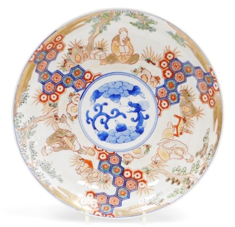 A Qing Dynasty late 19thC Imari dish, decorated with reserves of scholars in a garden, centrally with a dragon, 30cm wide.