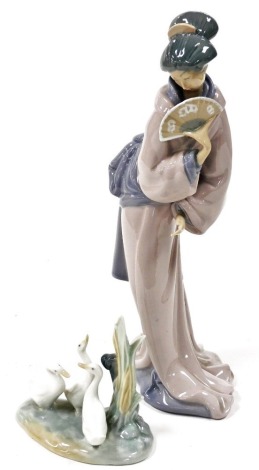 A Nao porcelain figure of a Japanese geisha girl, holding a fan, 32.5cm high, and a Nao figure of three ducks. (2)