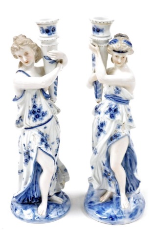 A pair of late 19thC Continental porcelain figural candle holders, modelled as Neoclassical ladies in semi attire, printed with flowers, gilt highlighted, 31cm high.