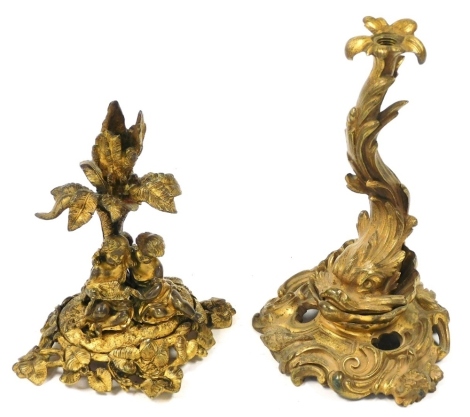 A late 19thC Continental ormolu candle holder, of branch form fronted by two children and a dove, raised on an oval leaf scroll base, 14cm high, together with an ormolu base, possibly from a candlestick, cast as a dolphin on a rococo scrolling wave and sh