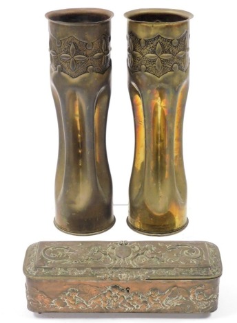 A pair of brass trench art shell case vases, 29cm high, together with a late 19thC Continental copper jewellery casket, embossed with cherubs playing musical instruments, with purple velvet lined interior, 24cm wide. (AF)