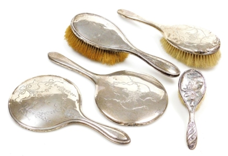 A group of silver mounted dressing table items, to include a matching mirror and hairbrush, each decorated with an engraved basket of flowers, with swags and bows, Birmingham 1924, a further hairbrush with repeat decoration to border, hallmarks rubbed, a 