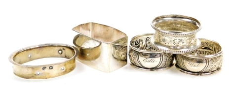 A group of silver napkin rings, comprising a pair of late 19th/early 20thC napkin rings, decorated with scrolls and leaves, each engraved with a shield cartouche for Bob and Edie, two further examples and a silver mount possibly for a bottle, 2.36oz all i