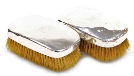 A pair of George V silver mounted clothes brushes, each with engine turned decoration and engraved monogram for AO, Birmingham 1931 and 1934, each 13cm wide.