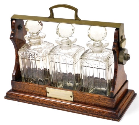 A 20thC oak tantalus, the case fitted with three cut glass decanters, with brass cap ends and swing handle, no key, 30cm high, 35cm wide, 17cm deep.