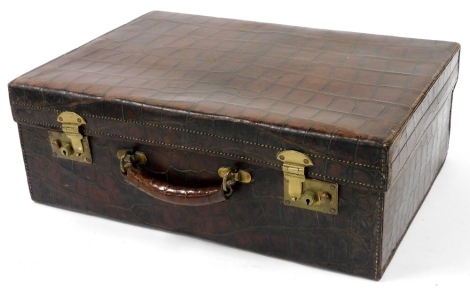 An early 20thC brown crocodile skin leather suitcase, with brass mounts, the hinged lid enclosing a pink satin interior (interior AF), 17cm high, 50cm wide, 35cm deep when laid flat.