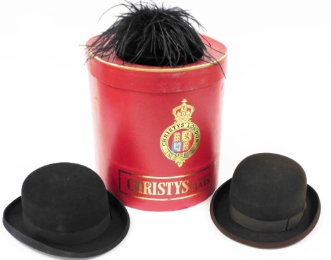 A Christy's London Hats red cardboard hat box, containing two Joule and Sons bowler hats, size 54 - 6&#8541?, in brown and black, and a Pauline for Bermona lady's fascinator, in black velvet with feather and diamante decoration.