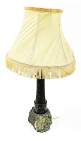 A Cornish serpentine table lamp, modelled as a lighthouse on a rock, with shade, 60cm high.