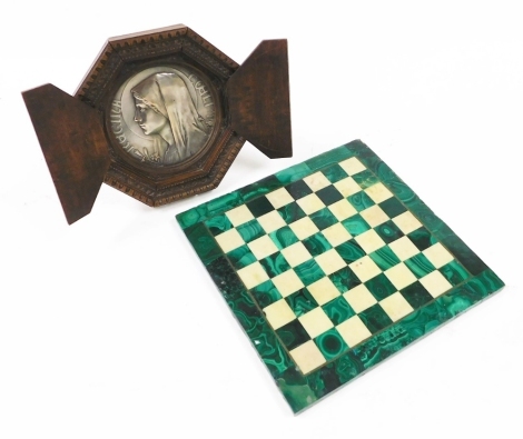 A malachite and white marble chess board, 27.5cm wide, together with an early 20thC silver plated Regina Coeli circular devotional plaque, signed indistinctly, in a carved beechwood strut octagonal frame, 20cm wide.