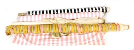 Four bolts of fabric, three striped, one white plain.