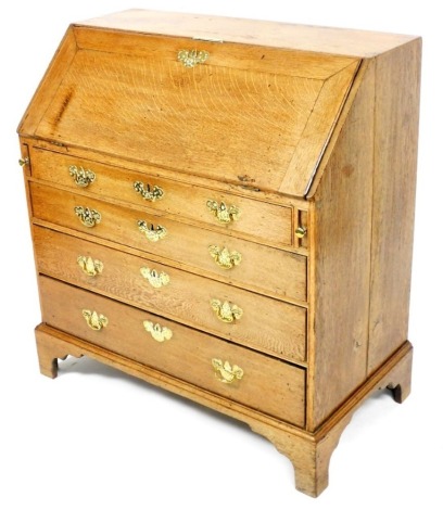 A George III oak bureau, the fall enclosing a fitted interior above four graduated drawers, each with pierced brass handles, on bracket feet, 100cm high, 91cm wide.