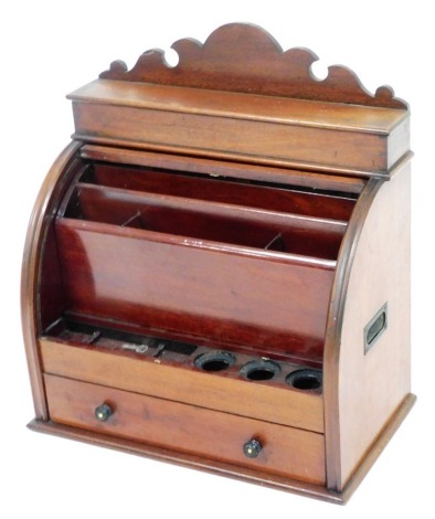 A late 19th/ early 20th mahogany desk stand, the top with a shaped crest above a hinged lid, the tambour front enclosing a space for ink bottles, pigeon holes, etc., above drawer with ebonised handles, 52cm high.