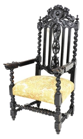 A late Victorian ebonised oak open armchair, the back with lion carved crest, spirally turned supports, the arms terminating in masks, with a padded seat on spirally turned supports with H stretcher.