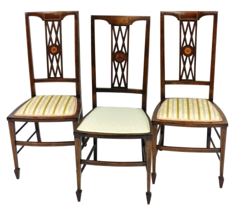 A set of three Edwardian mahogany and satinwood crossbanded bedroom chairs, each with a pierced splat, centred with an Art Nouveau marquetry roundel, a padded seat on square tapering legs.