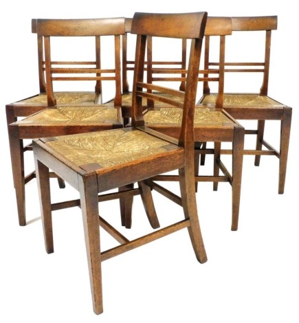 A set of six country made oak dining chairs, each with a bar back and a rush seat, on square tapering legs with H stretcher.