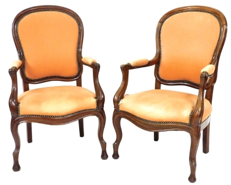 A pair of Continental walnut show frame open armchairs, each with a padded back and seat, on cabriole legs. The upholstery in this lot does not comply with the 1988 (Fire & Fire Furnishing) Regulations, unless sold to a known exporter or upholsterer it w