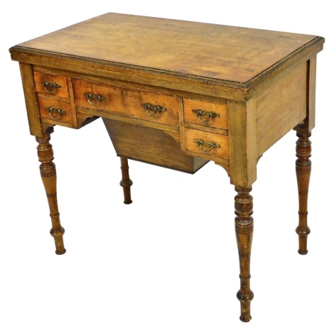 A Victorian burr elm games/work table by T. Simpson & Sons, Cabinet Makers, Halifax, the hinged rectangular top with a moulded edge enclosing a baize lined interior and markers, above an arrangement of five drawers and a wool bag drawer, on turned taperin