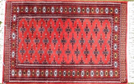 A Caucasian red ground rug, decorated with repeating geometric motifs within repeating borders, 82cm x 120cm.