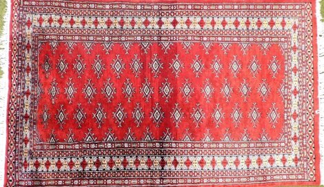 A Caucasian red ground rug, decorated with repeating geometric motifs within repeating borders, 95cm x 152cm.